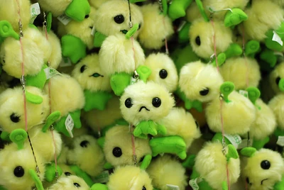 Many, many plush, green, smiling mobile phone charms.
