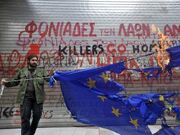 Greece-man-burning-flag-in-front-of-graffiti
