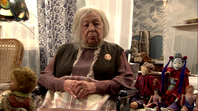 Datei:Frau Hennings sitzt in ihrem Zimmer.png