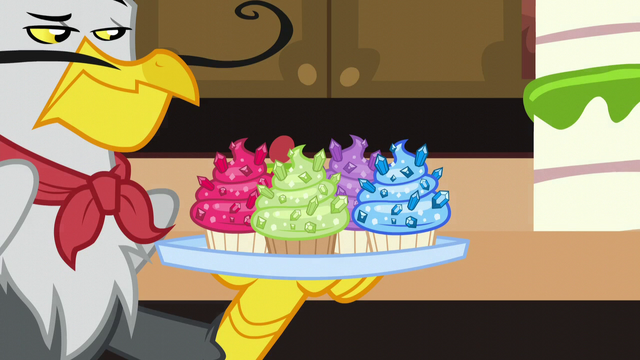 File:Gustave le Grand holding tray of jeweled cupcakes S5E10.png