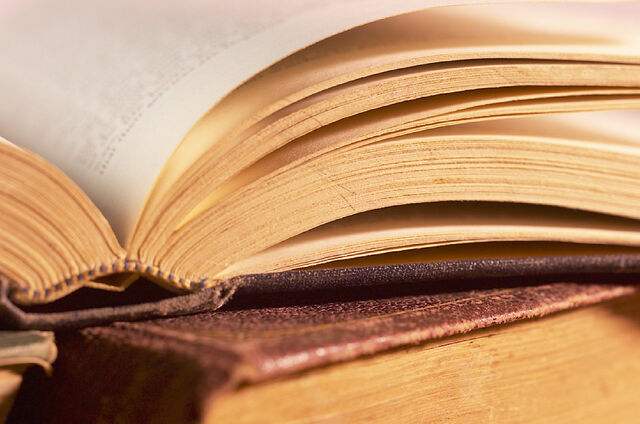 File:Open-book-on-top-of-pile-of-books.jpg